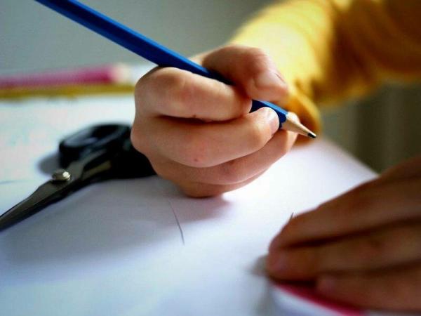Otroška roka s svinčnikom med prsti