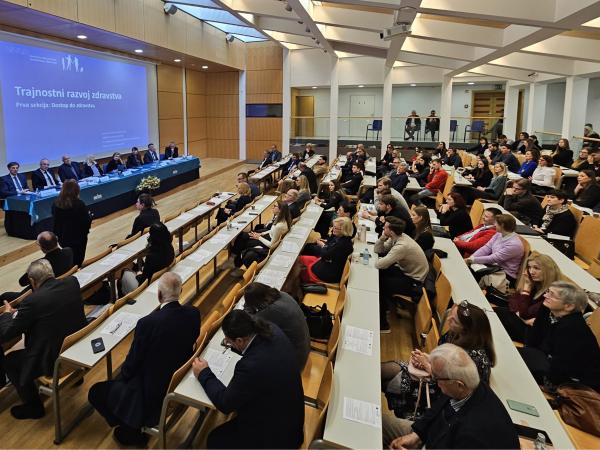 Udeleženci konference in varuhinja stoje med razpravo