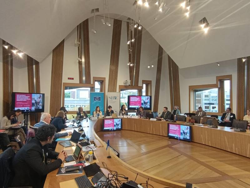 Dvorana, kjer je potekala konferenca. Vidni so udeleženvi za omizjem.