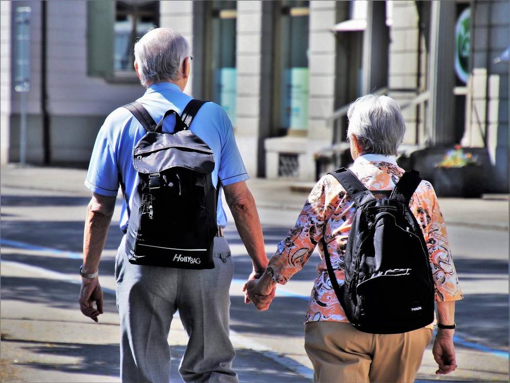 Stareši par se sprehaja držeč se za roke