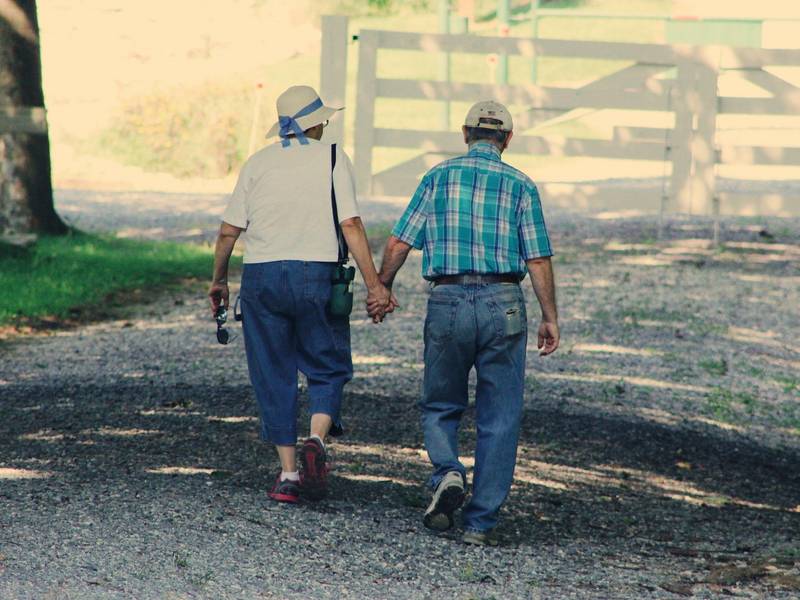 Starejša človeka se sprehajata držeč se za roke
