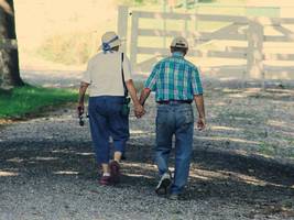 Two elderly people are walking holding hands