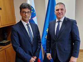 The Ombudsman and the President of the National Council stand in front of the flags  Ikona »Potrdila skupnost«